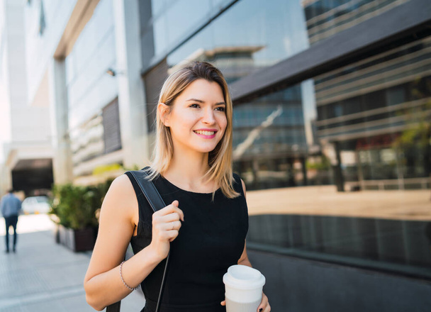 Portrait of young business woman walking to work while drinking takeaway coffee. Business and success concept. - Photo, Image