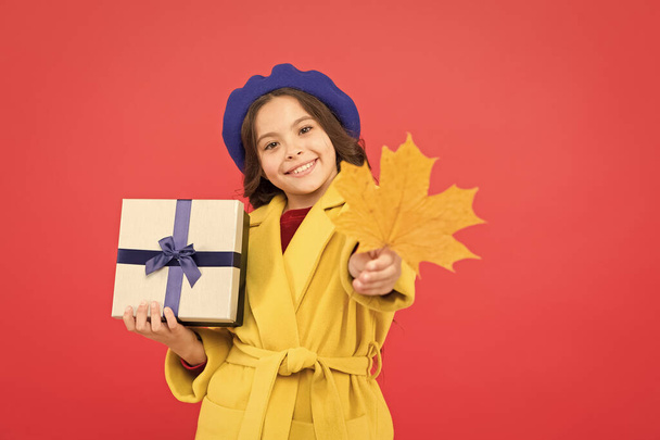 Ein tolles Gefühl. glückliches kleines Mädchen mit Ahornblatt und Geschenkbox. Mädchen in französischer Baskenmütze halten Geschenk. Herbstlicher Wetterumschwung. Erntedankfest. Herbstzeit. Einkaufen in der Schule. Kindermode im Herbst - Foto, Bild