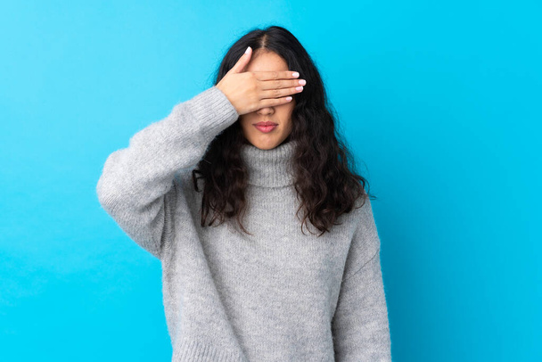 Donna cinese spagnola su sfondo blu isolato che copre gli occhi a mano. Non voglio vedere qualcosa. - Foto, immagini