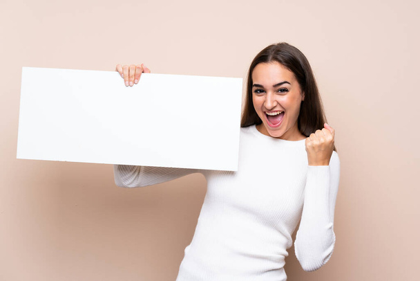 Young woman over isolated background holding an empty white placard for insert a concept - Foto, Imagen