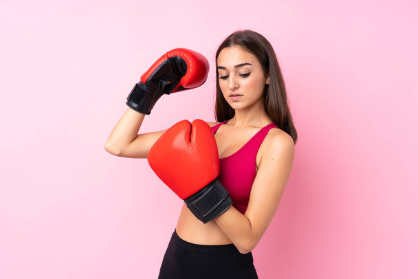 Юная спортсменка на изолированном розовом фоне в боксёрских перчатках - Фото, изображение