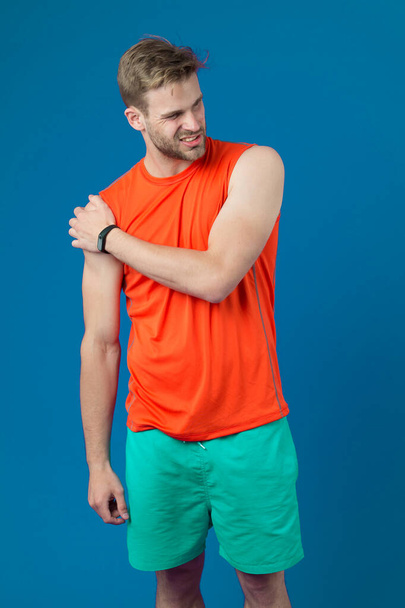 Sportsman touch shoulder on violet background. Muscular man feel pain after training or workout. Pain in shoulder. Sport injury. I need massage. Health care and treatment. Bodycare and wellness - Foto, afbeelding