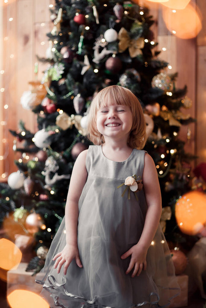 little girl standing infront of the christmas tree and waiting for Christmas, Santa Claus. Christmas and Happy New Year concept. - Фото, изображение