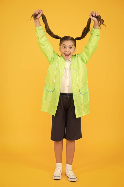 Rain is not hindrance. small girl have fun in raincoat. active schoolgirl waterproof cloak. water resistant clothes. in good mood. Come and enjoy discounts. Autumn fashion kid. dry and comfortable - 写真・画像
