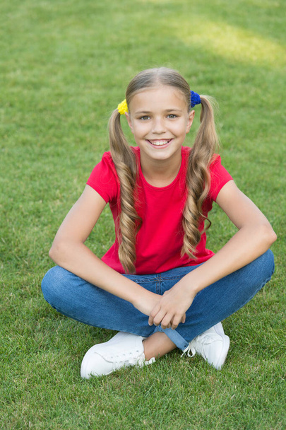 Little girl cute ponytails hairstyle relaxing on green grass, optimistic concept - Foto, imagen