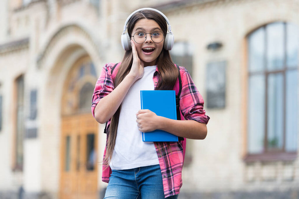 Amazing audio content. Surprised child listen to audio book outdoors. Audio lesson. New technology. English school. Learning foreign language. Modern life. Music education. All you need are your ears - Фото, зображення