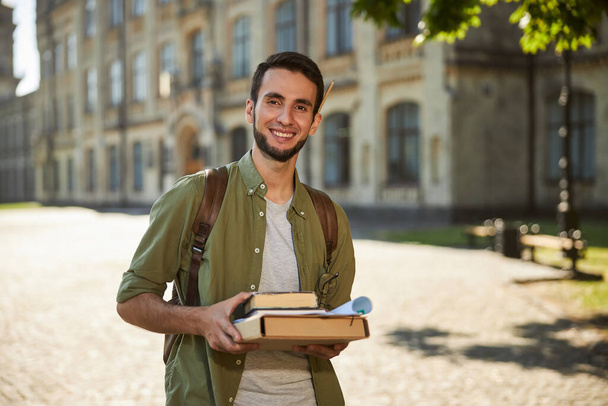 Handsome student holding books with both hands - Foto, Bild