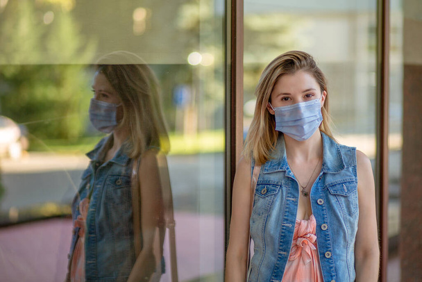 Beautiful businesswoman, young woman, in medical protective mask on her face, in formal jacket standing outdoors, looking at camera. Coronavirus, virus, epidemic, pandemic covid-19 concept - Foto, Bild