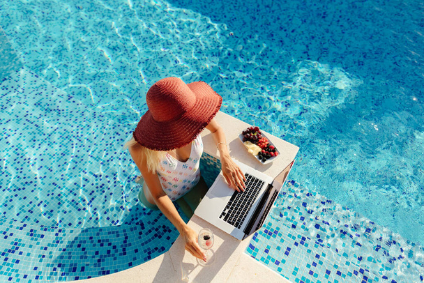 mujer usando el ordenador portátil y relajarse en la piscina - Foto, Imagen