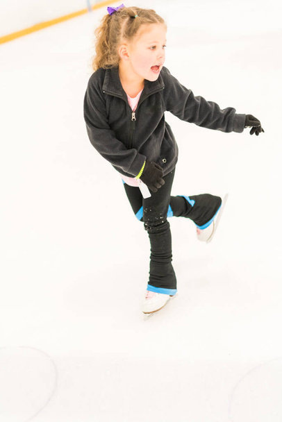Pieni taitoluistelija harjoittelee sisätiloissa jääareenalla. - Valokuva, kuva