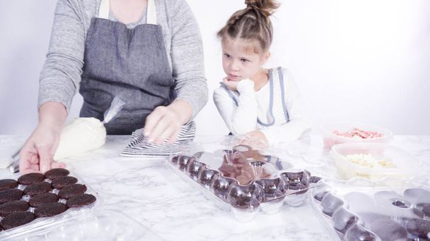 Adım adım. Küçük kız çikolatalı kekleri çikolatalı kar taneleriyle süslemeye yardım ediyor.. - Fotoğraf, Görsel