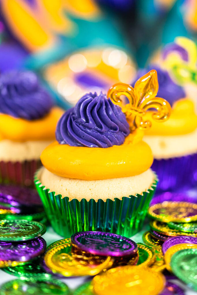 Mardi Gras vanília muffinok fóliás süteményben és olasz vajkrém cukormázzal díszítve. - Fotó, kép