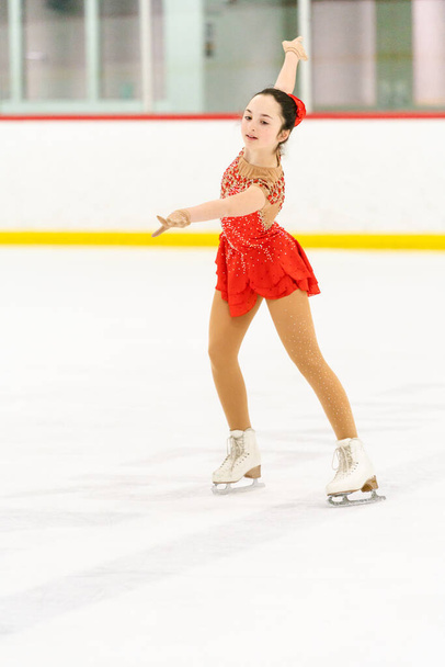 Teenage girl practicing figure skating on an indoor ice skating rink. - Photo, Image