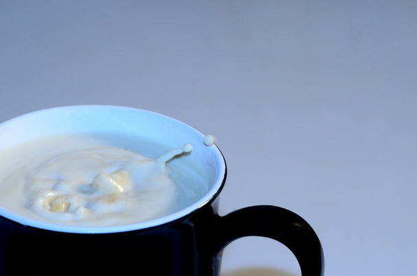 cup with milk and drops at the edge - Photo, Image