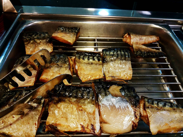 Viipale grillattua ja paistettua sabaa teräksen ritilätarjottimella ruokaa pihdeillä. Terveellistä ruokaa ja tuoretta kalaa - Valokuva, kuva