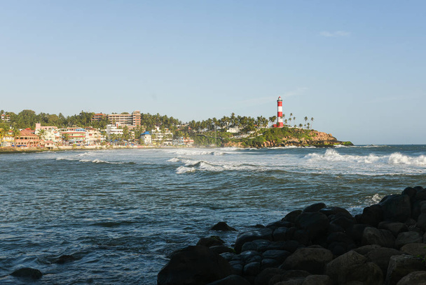 Κεράλα, Ινδία - Σεπτέμβριος 08, 2019: Kovalam παραλία και Vizhinjam φως σπίτι. Θαλάσσια κύματα κινούνται προς την ακτή. - Φωτογραφία, εικόνα