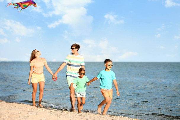 リゾートで海のビーチで幸せな家族の飛行カイト - 写真・画像