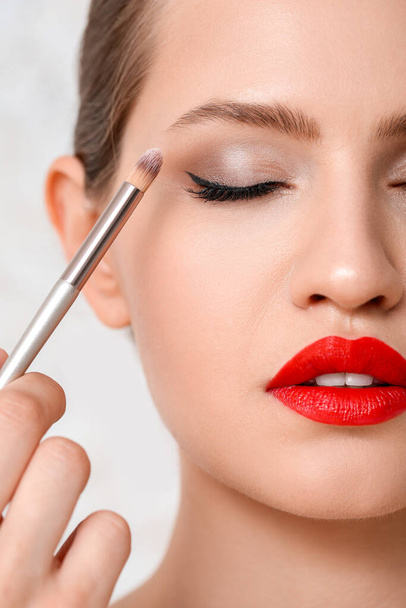 Makeup artist working with model on light background, closeup - Photo, Image