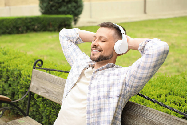 Pohledný muž poslouchající hudbu při relaxaci v parku - Fotografie, Obrázek
