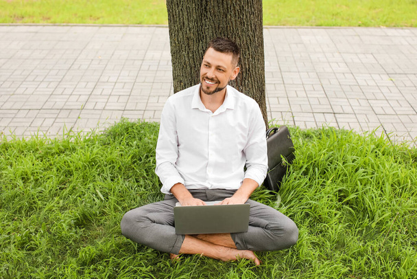 Bonito homem de negócios com laptop relaxante no parque - Foto, Imagem