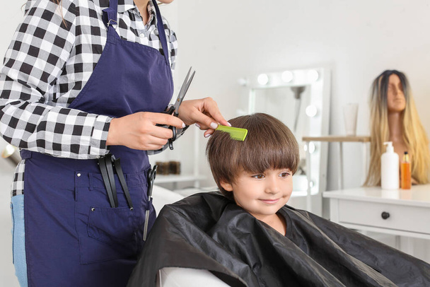 Female hairdresser working with little boy in salon - Foto, Bild