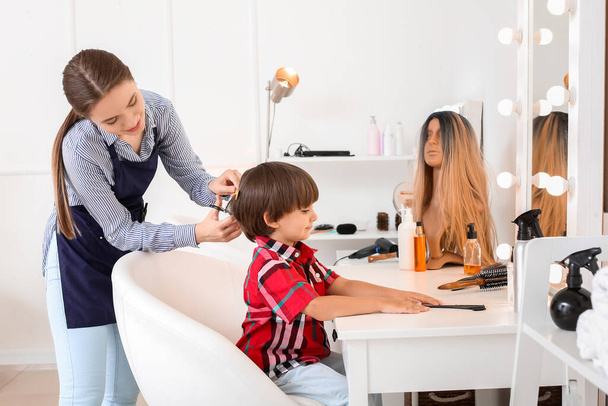 Female hairdresser working with little boy in salon - Фото, изображение