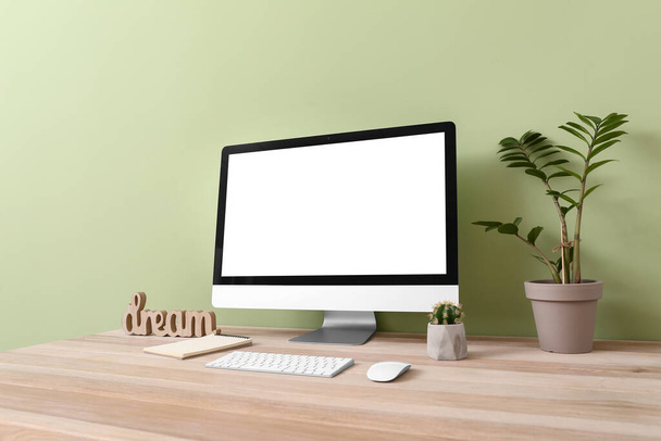 Σύγχρονη οθόνη υπολογιστή στο τραπέζι κοντά στον τοίχο χρώμα - Φωτογραφία, εικόνα