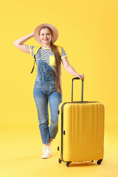 色の背景にスーツケース付きの若い女性。旅行のコンセプト - 写真・画像