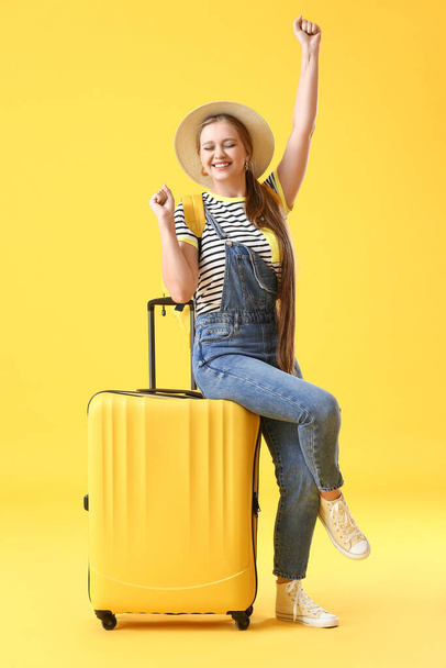 Young woman with suitcase on color background. Travel concept - Фото, изображение