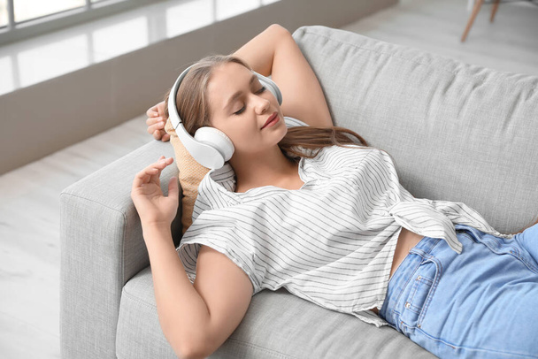 Sleepy young woman listening to music at home - Fotó, kép