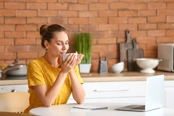 Beautiful young woman drinking tea while working at home - Photo, Image