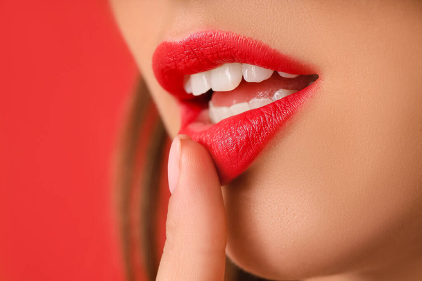 Young woman with beautiful red lipstick on color background, closeup - Foto, afbeelding
