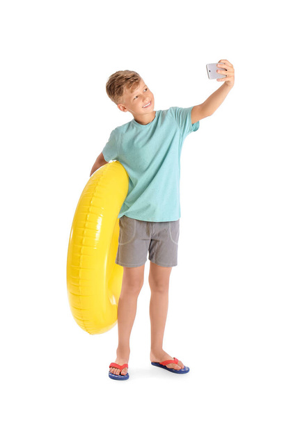 Χαριτωμένο μικρό αγόρι με φουσκωτό δαχτυλίδι λήψη selfie σε λευκό φόντο - Φωτογραφία, εικόνα