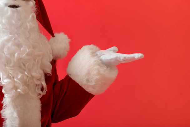Der Weihnachtsmann hält etwas auf farbigem Hintergrund - Foto, Bild