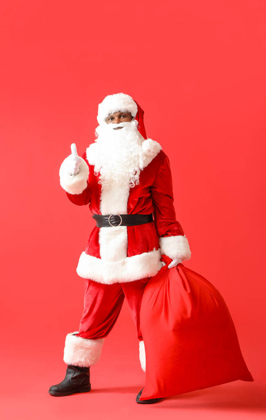 Santa Claus afroamericano con bolsa sobre fondo de color - Foto, Imagen