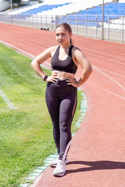 Spor giyimli bir kadın stadyumda duruyor.. - Fotoğraf, Görsel