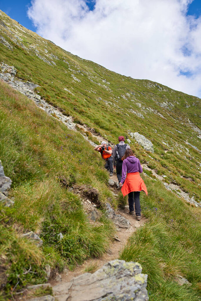 Family of hikers climbing a steep path into the mountains - Fotoğraf, Görsel