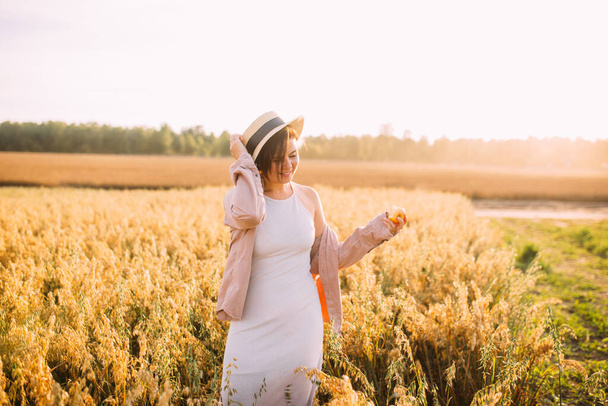 a girl in a straw hat in a field with an apple - Fotoğraf, Görsel