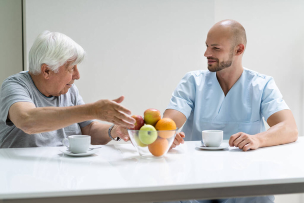 Caretaker In Retirement Home With Elder Man - Foto, afbeelding