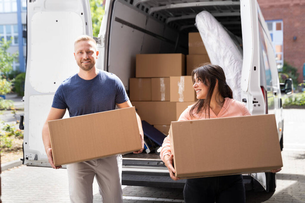 Couple Moving Boxes From Van Or Truck Together Outdoors - Foto, imagen