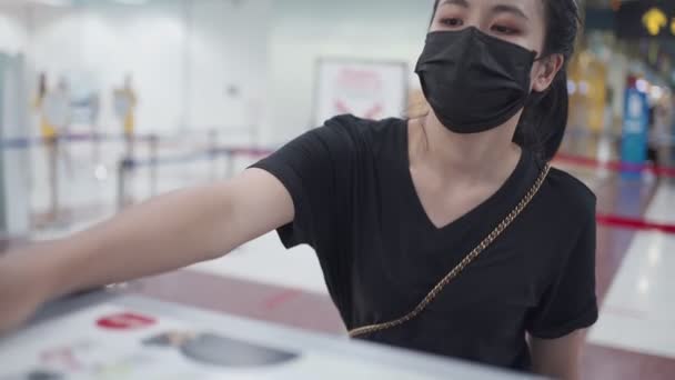Junge Asiatinnen geben ihren Ausweis, Personalausweis, Reisepass zum Check-in-Schalter am Flughafenterminal, registrieren Sie sich für den Flug, buchen Ticket-Bordkarte, covid-19 neue normale Reise soziale Entfernung  - Filmmaterial, Video