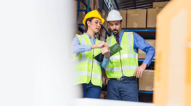 Manager of warehouse worker assign and command in serious look to assistant manager woman in local warehouse or factory, Asian and white caucasian people,Partner and colleague working together concept - Photo, Image
