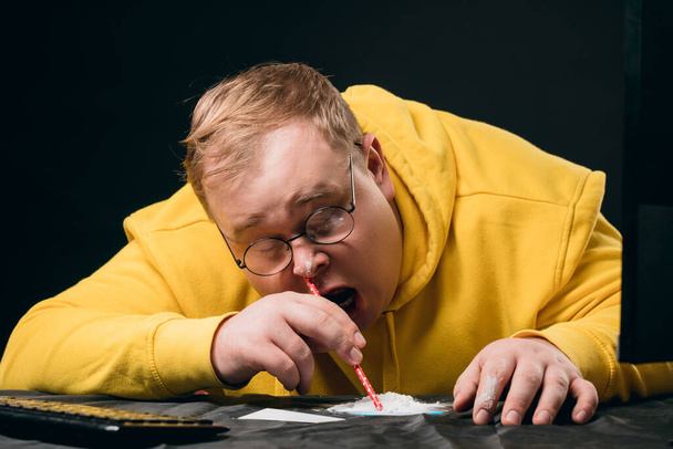 vyčerpaný opilý předávkovaný chlap oblečený ve žluté mikině, čichá k drogám - Fotografie, Obrázek
