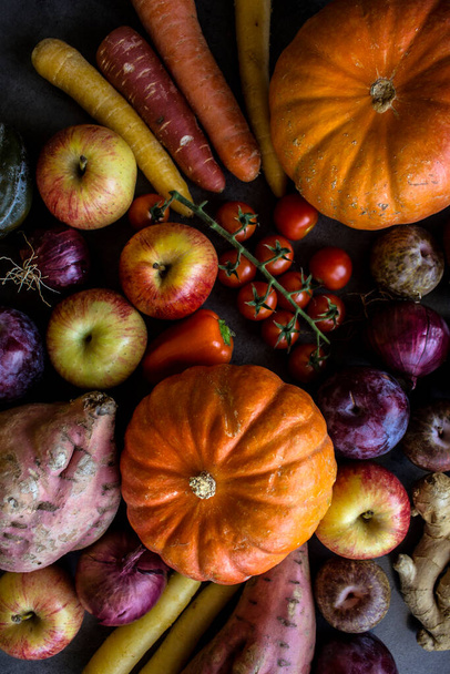 灰色のテーブルの上に新鮮な野菜。バターナッツ、宝石のカボチャ、カボチャ、黄金のナゲット、ニンジン、チェリートマト、リンゴ、サツマイモ、赤玉ねぎのトップビューの写真。秋の収穫.  - 写真・画像