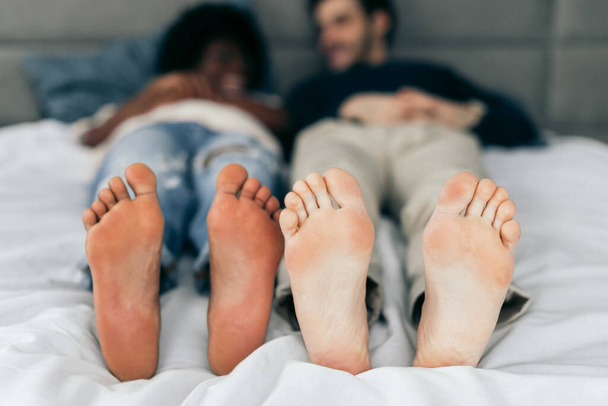 Close-up of feet of interracial couple sleeping together. - Фото, зображення