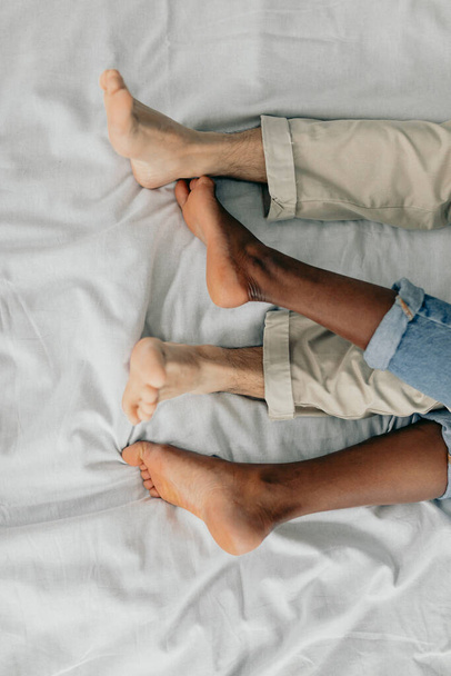 Close-up of feet of interracial couple sleeping together. - Fotó, kép