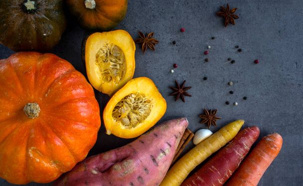 Frisches Herbstgemüse auf grauem, strukturiertem Hintergrund mit Kopierraum. Foto von oben mit Kürbis, Karotte, Süßkartoffeln und Gewürzen. Herbsternte. Konzept der gesunden Ernährung.  - Foto, Bild