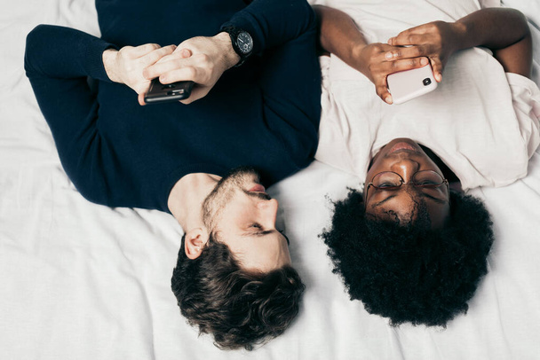 mixed race family couple chat with friends lying in bed, dressed casual - Photo, Image