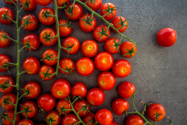 Beaucoup de tomates cerises sur une table. Fond gris. Photo de vue du dessus de légumes frais.  - Photo, image