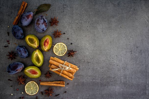 Bâtonnets de cannelle, prunes et citron séché sur fond texturé gris foncé avec espace de copie.  - Photo, image